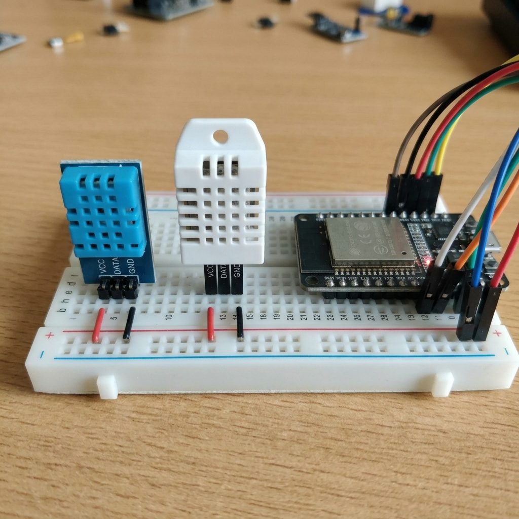DHT11 azul y DHT22 blanco lado a lado en una protoboard junto a un ESP32